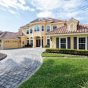 Elegant home with a stylish driveway featuring unique paver patterns, surrounded by lush greenery and decorative landscaping, showcasing the aesthetic appeal of Coastal Driveway Pavers.