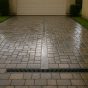 Wet paver driveway after a Florida rainstorm with a channel drain across the garage threshold