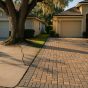 Cracked concrete driveway lifted by live oak roots next to an interlocking concrete paver driveway in a Jacksonville neighborhood